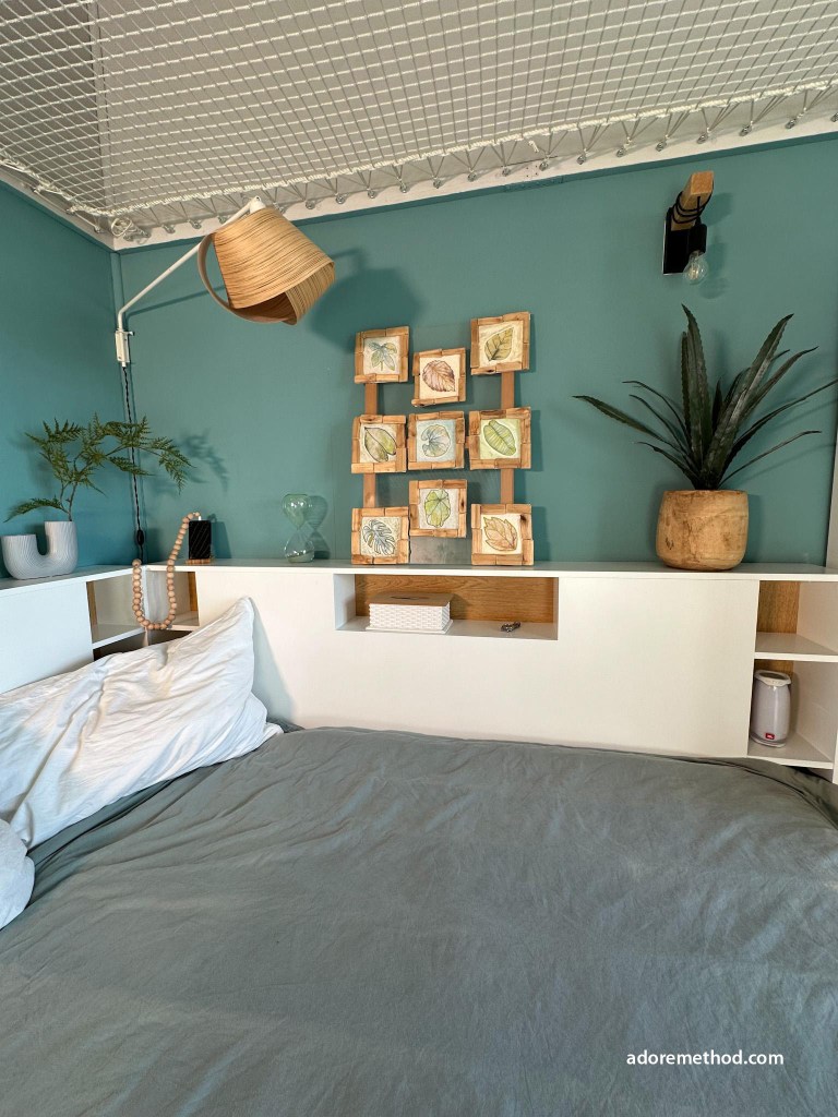 Tête de lit avec rangements intégrés, mur bleu canard, décoration naturelle et filet.