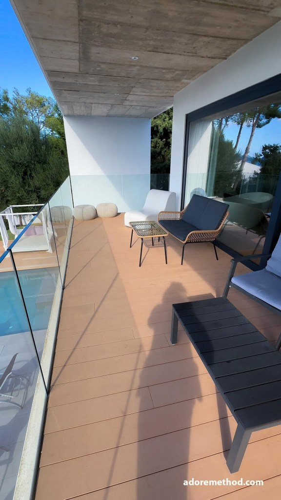 Un balcon spacieux avec une vue verdoyante, des fauteuils modernes et une table basse minimaliste.